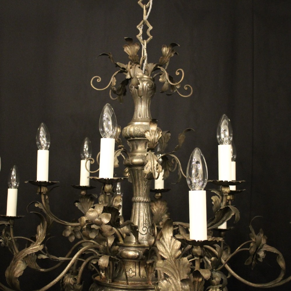 An antique Italian Genoa twelve-light chandelier crafted from gilded metal featuring ornate leaf motifs and scrolling arms supporting candle bulb holders. View IV