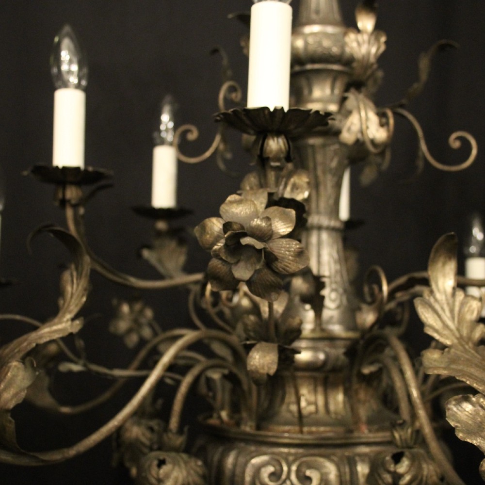An antique Italian Genoa twelve-light chandelier crafted from gilded metal featuring ornate leaf motifs and scrolling arms supporting candle bulb holders. View VI