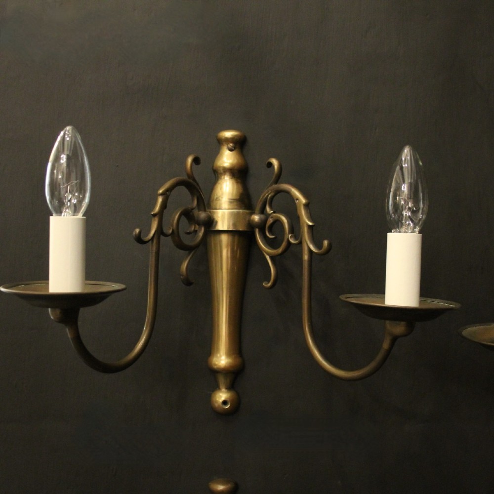 A set of four matching antique brass twin-arm wall sconces featuring curved scrollwork and candle-style bulb sockets. View II