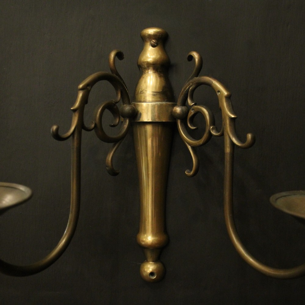 A set of four matching antique brass twin-arm wall sconces featuring curved scrollwork and candle-style bulb sockets. View III