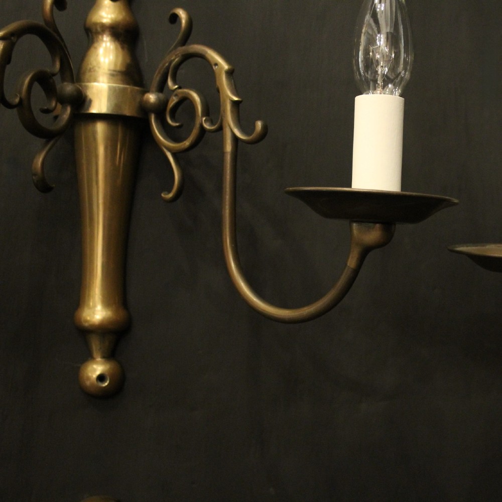A set of four matching antique brass twin-arm wall sconces featuring curved scrollwork and candle-style bulb sockets. View V