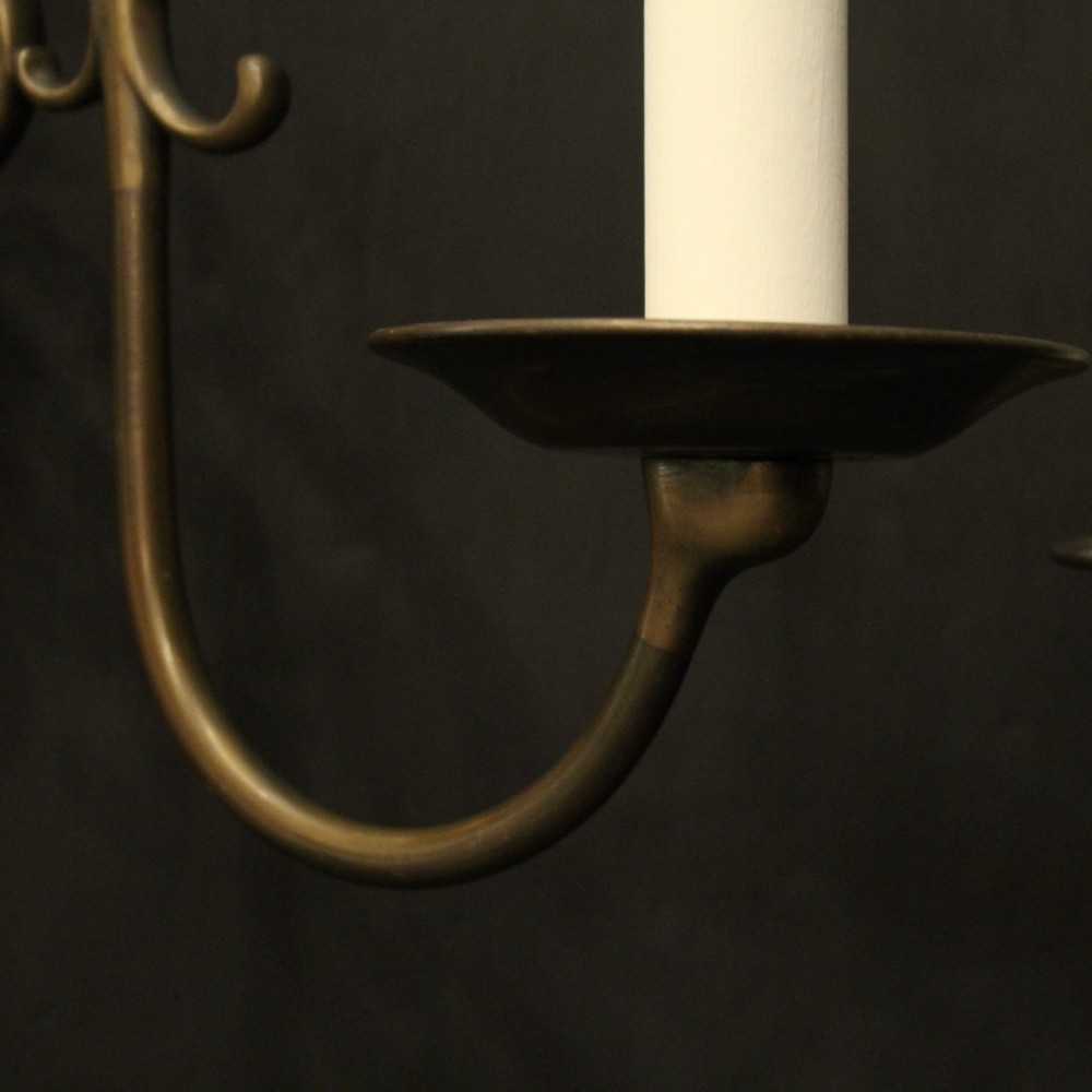 A set of four matching antique brass twin-arm wall sconces featuring curved scrollwork and candle-style bulb sockets. View VI