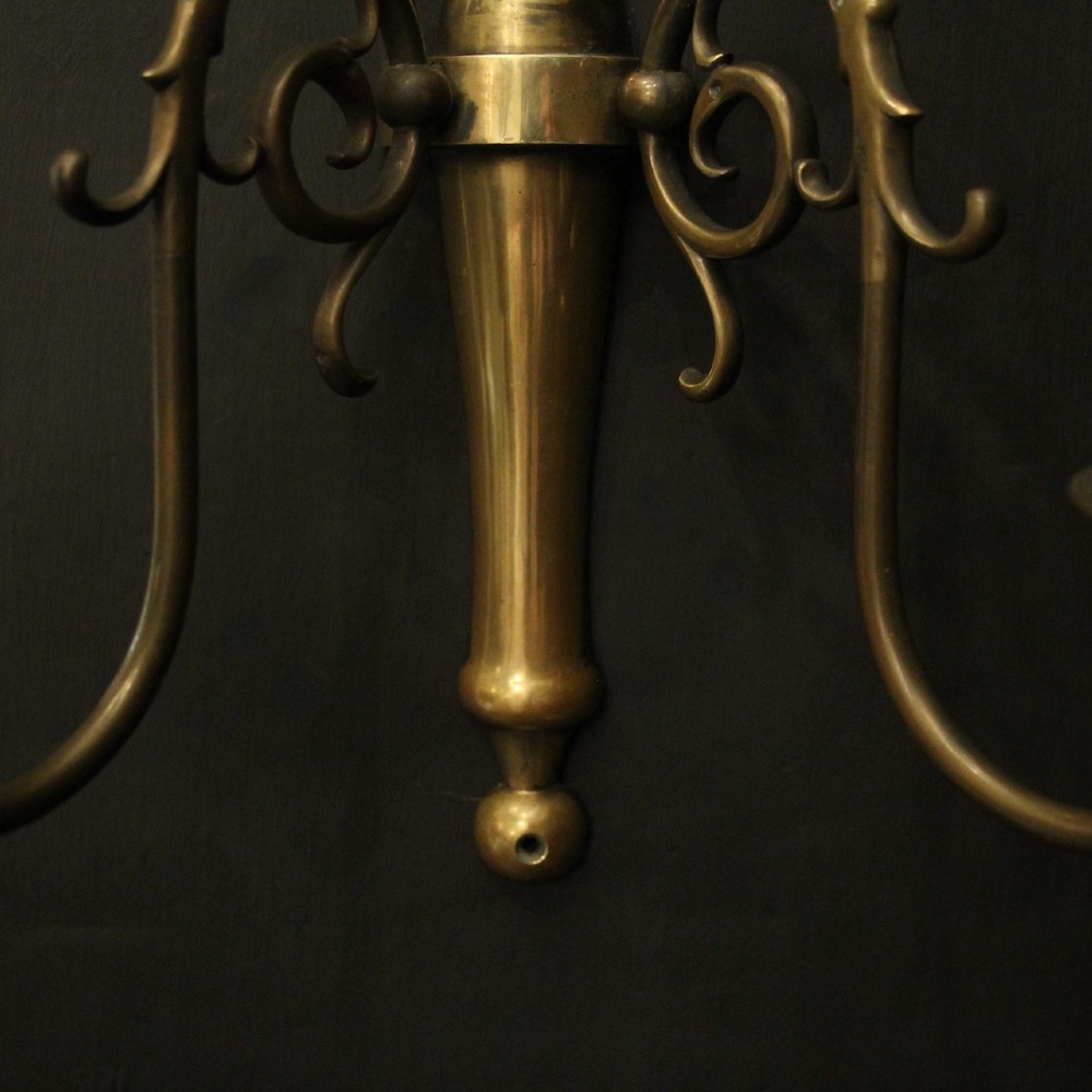 A set of four matching antique brass twin-arm wall sconces featuring curved scrollwork and candle-style bulb sockets. View VII