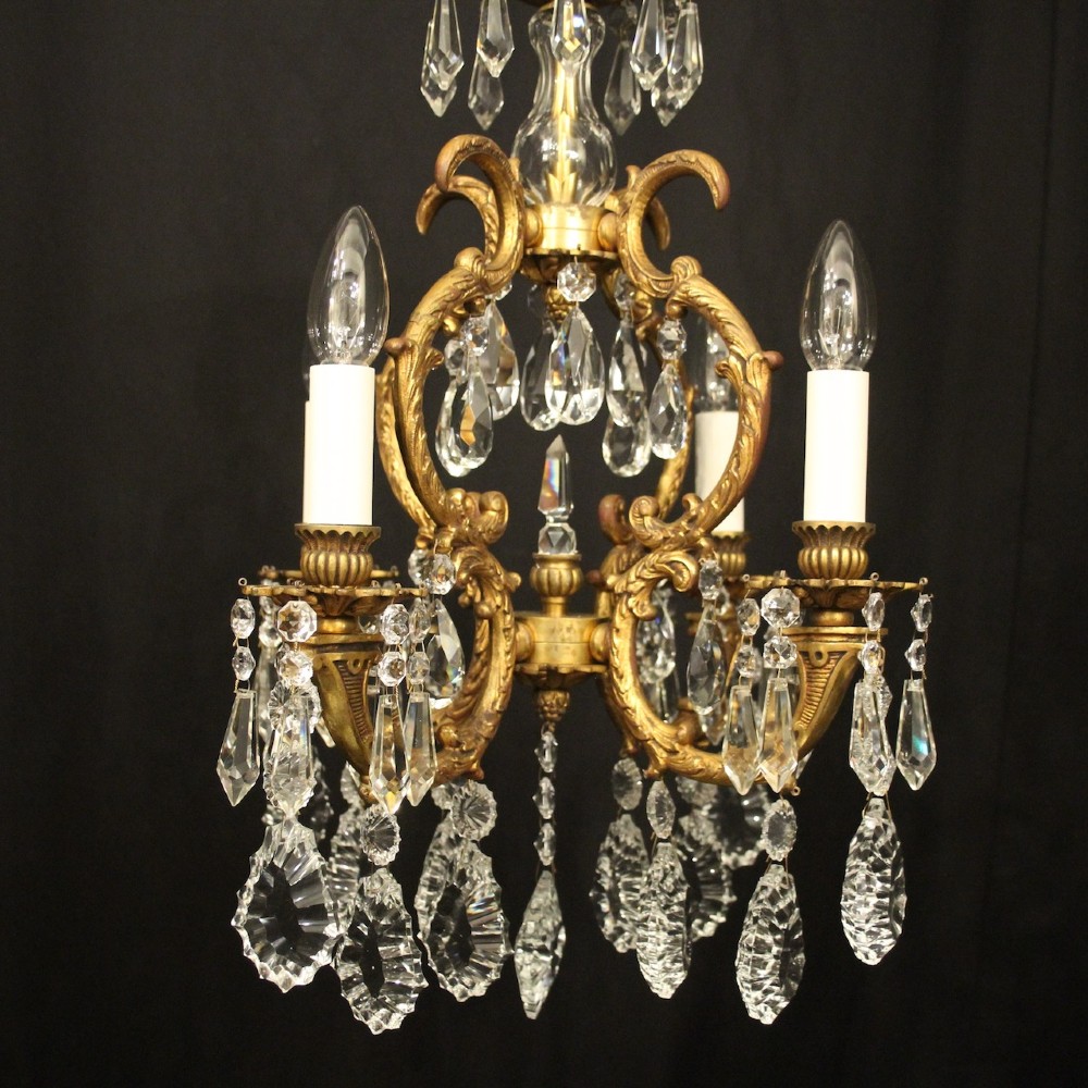An antique French four-light chandelier featuring a scrollwork gilt bronze frame hung with faceted crystal drops. View II