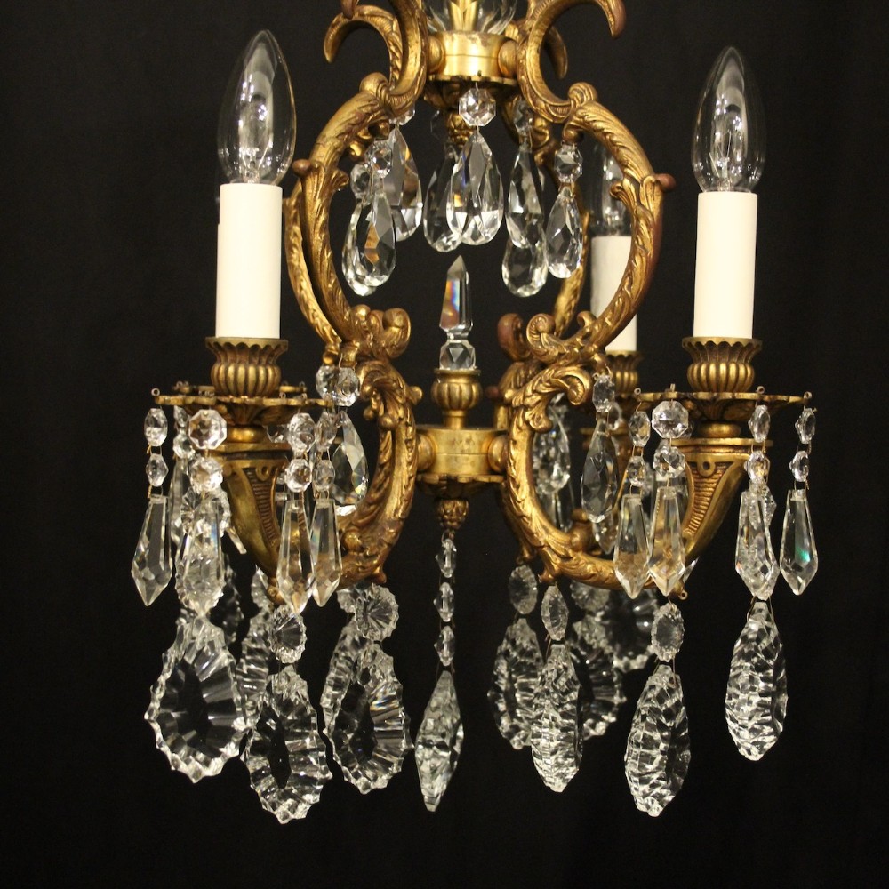 An antique French four-light chandelier featuring a scrollwork gilt bronze frame hung with faceted crystal drops. View III