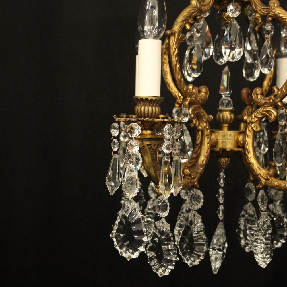 An antique French four-light chandelier featuring a scrollwork gilt bronze frame hung with faceted crystal drops. View IV