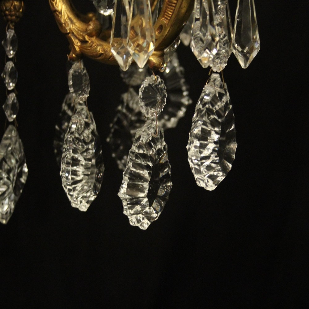 An antique French four-light chandelier featuring a scrollwork gilt bronze frame hung with faceted crystal drops. View VI