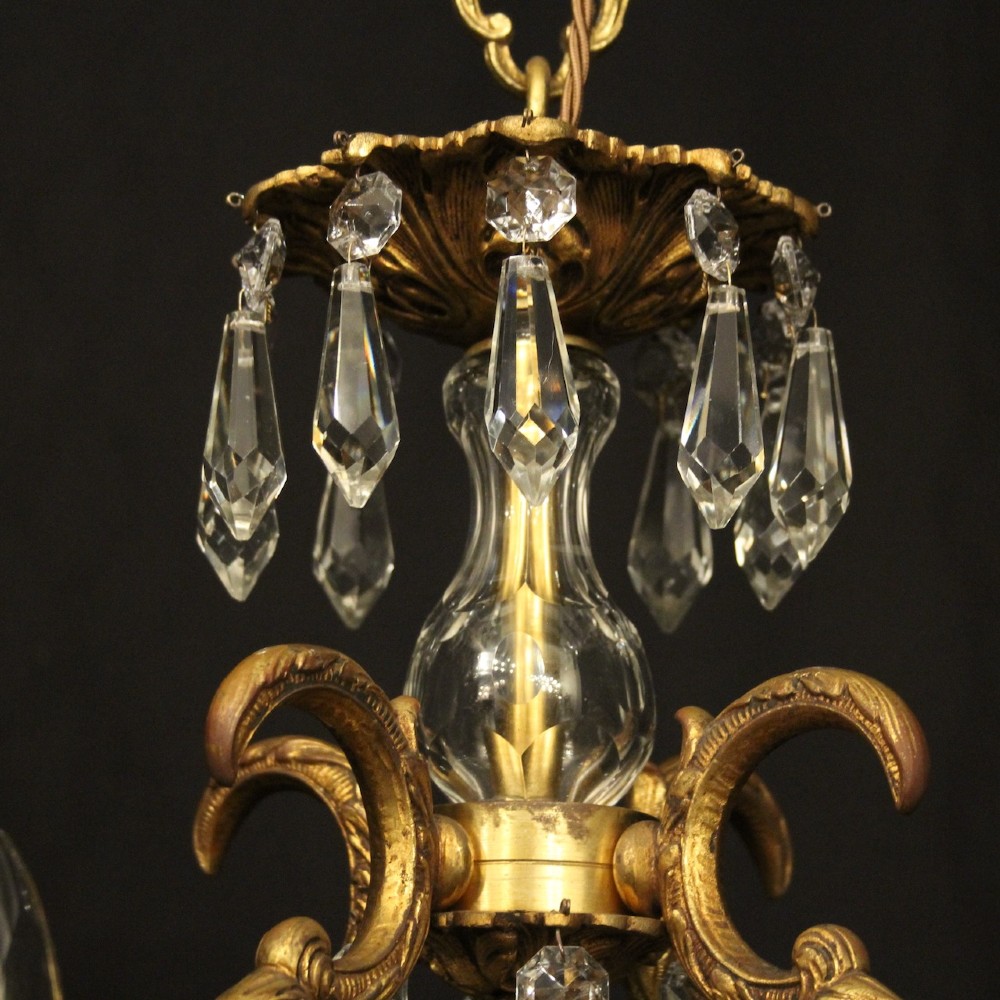 An antique French four-light chandelier featuring a scrollwork gilt bronze frame hung with faceted crystal drops. View IX
