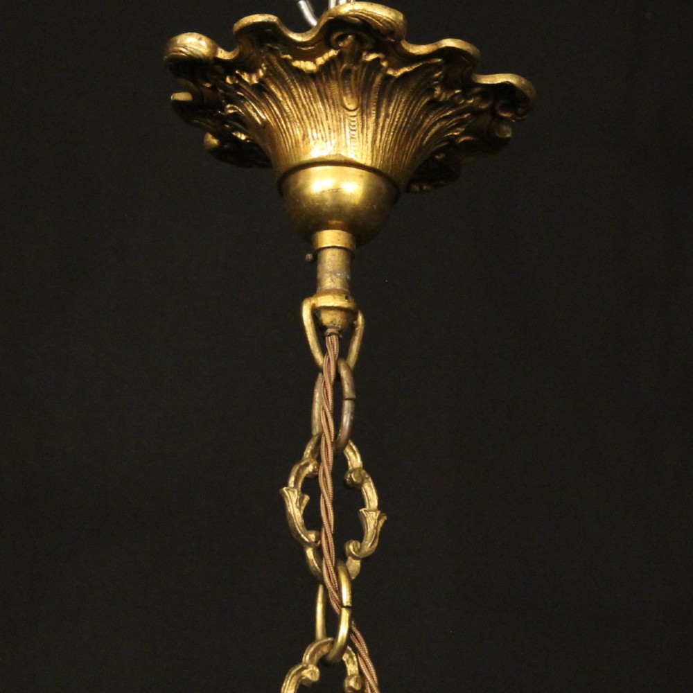 An antique French four-light chandelier featuring a scrollwork gilt bronze frame hung with faceted crystal drops. View X
