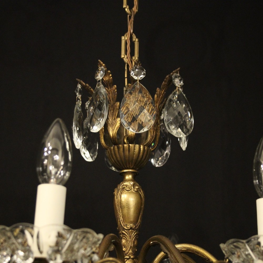 An eight-arm gilded metal chandelier suspended from a chain, decorated with faceted glass droplets and glass candle-style light holders. View VII