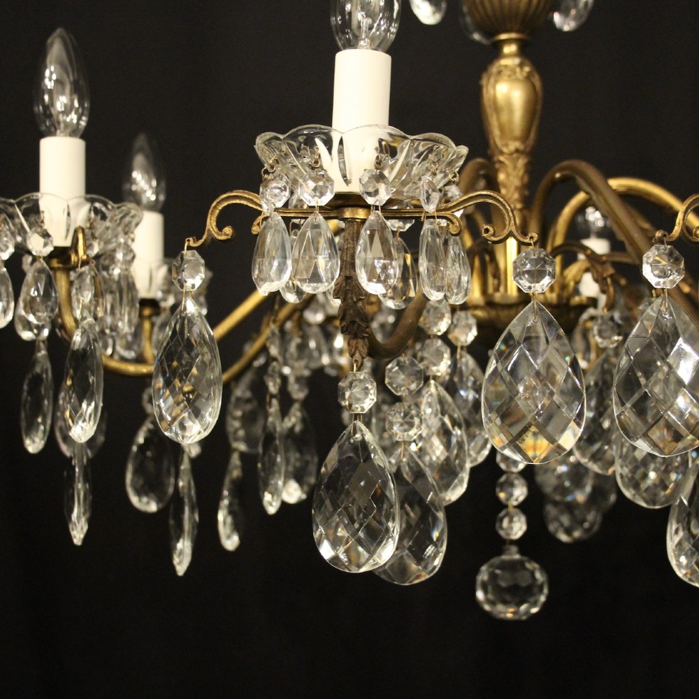 An eight-arm gilded metal chandelier suspended from a chain, decorated with faceted glass droplets and glass candle-style light holders. View VIII