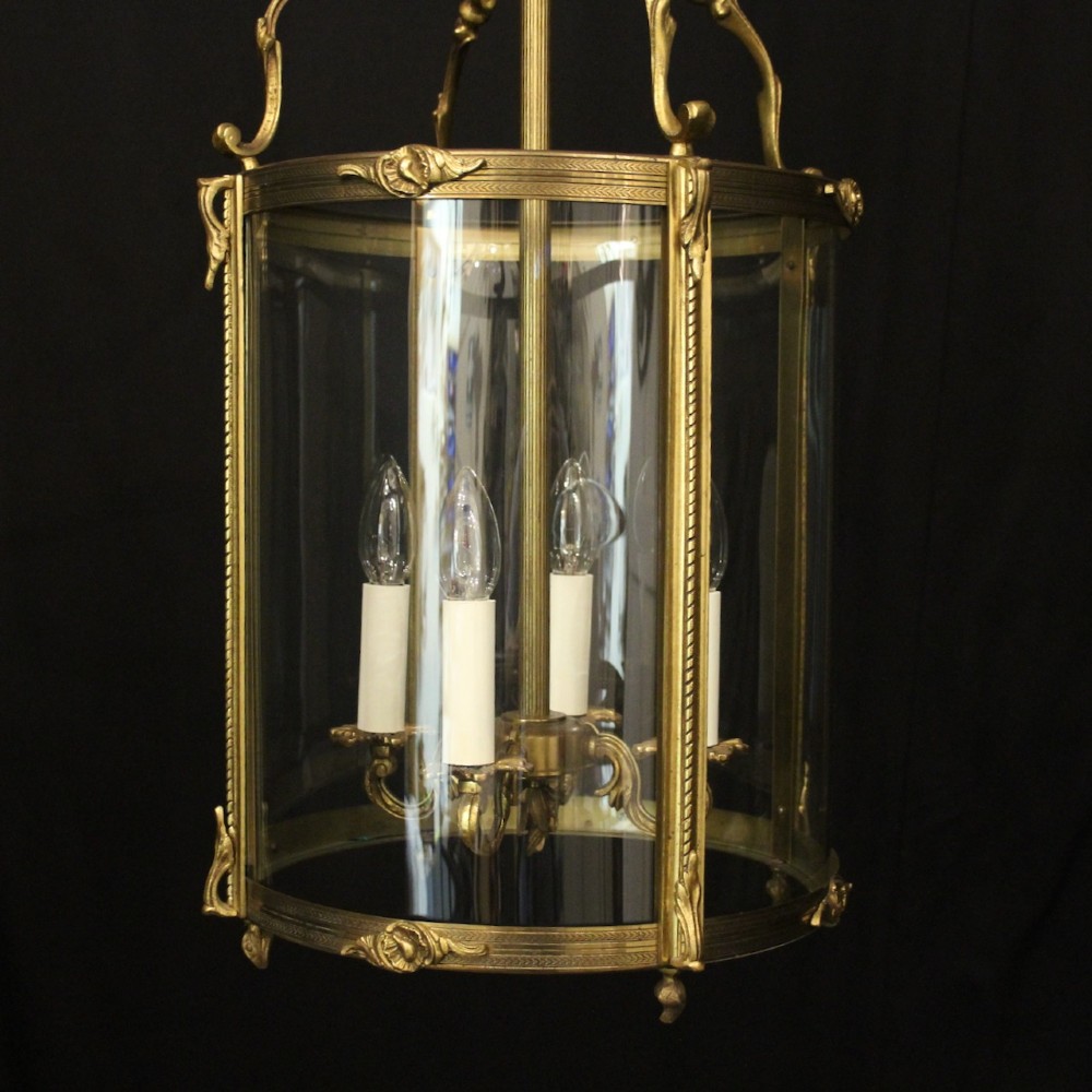 An antique French gilded bronze hall lantern featuring convex glass panels surrounding a four-light candle-style fixture with ornate scrollwork top brackets. View II