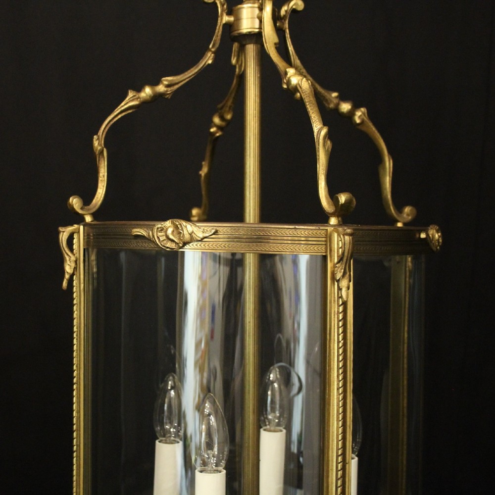 An antique French gilded bronze hall lantern featuring convex glass panels surrounding a four-light candle-style fixture with ornate scrollwork top brackets. View III