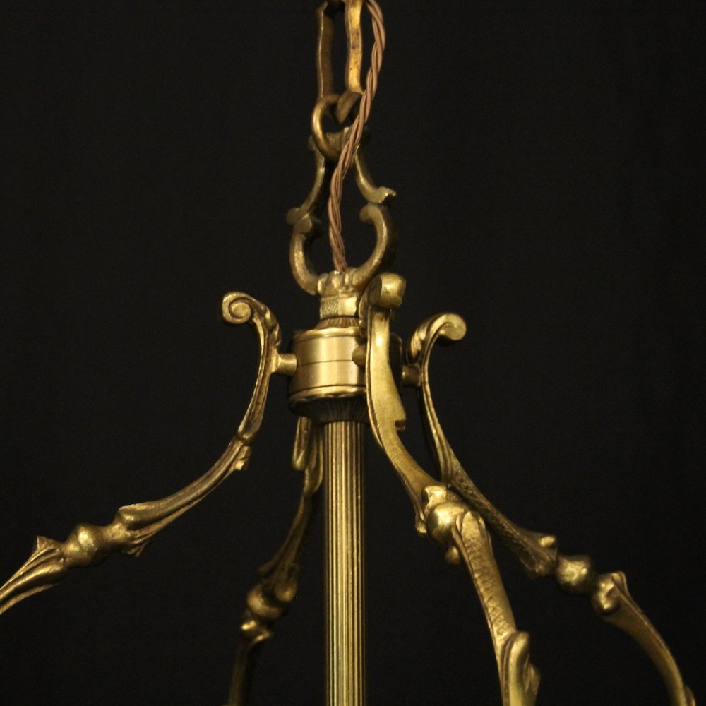 An antique French gilded bronze hall lantern featuring convex glass panels surrounding a four-light candle-style fixture with ornate scrollwork top brackets. View V