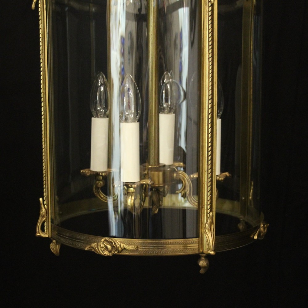 An antique French gilded bronze hall lantern featuring convex glass panels surrounding a four-light candle-style fixture with ornate scrollwork top brackets. View VI