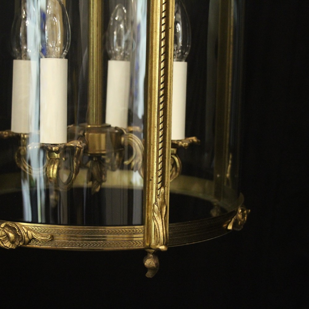 An antique French gilded bronze hall lantern featuring convex glass panels surrounding a four-light candle-style fixture with ornate scrollwork top brackets. View VII