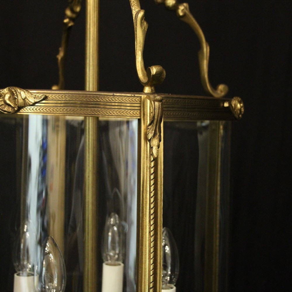 An antique French gilded bronze hall lantern featuring convex glass panels surrounding a four-light candle-style fixture with ornate scrollwork top brackets. View VIII