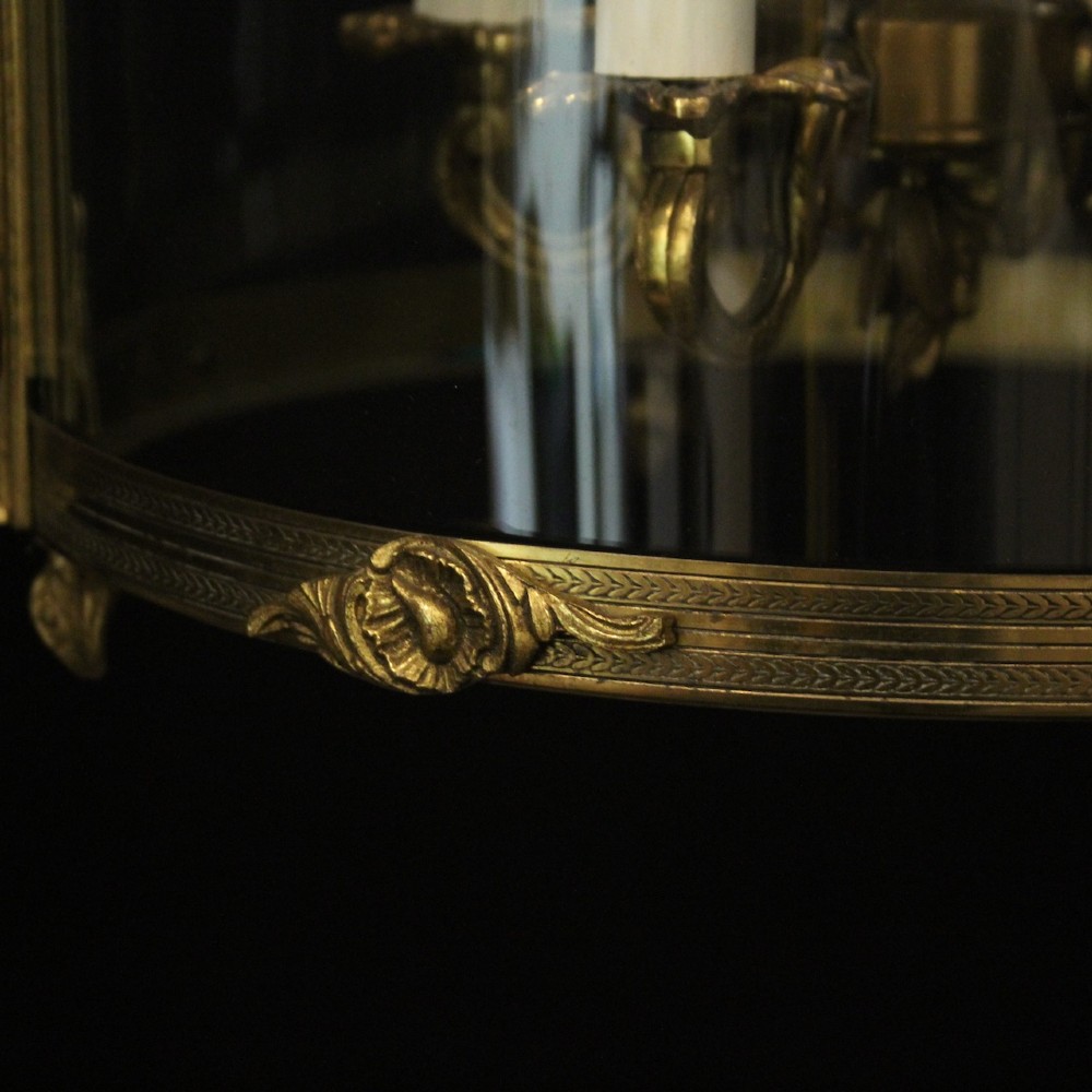 An antique French gilded bronze hall lantern featuring convex glass panels surrounding a four-light candle-style fixture with ornate scrollwork top brackets. View IX