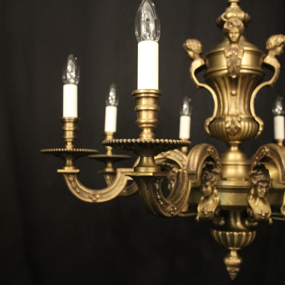 An eight-arm French gilt bronze chandelier featuring an urn-shaped central stem, cast classical busts, and candle-style bulb holders. View II