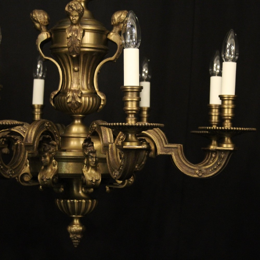 An eight-arm French gilt bronze chandelier featuring an urn-shaped central stem, cast classical busts, and candle-style bulb holders. View III