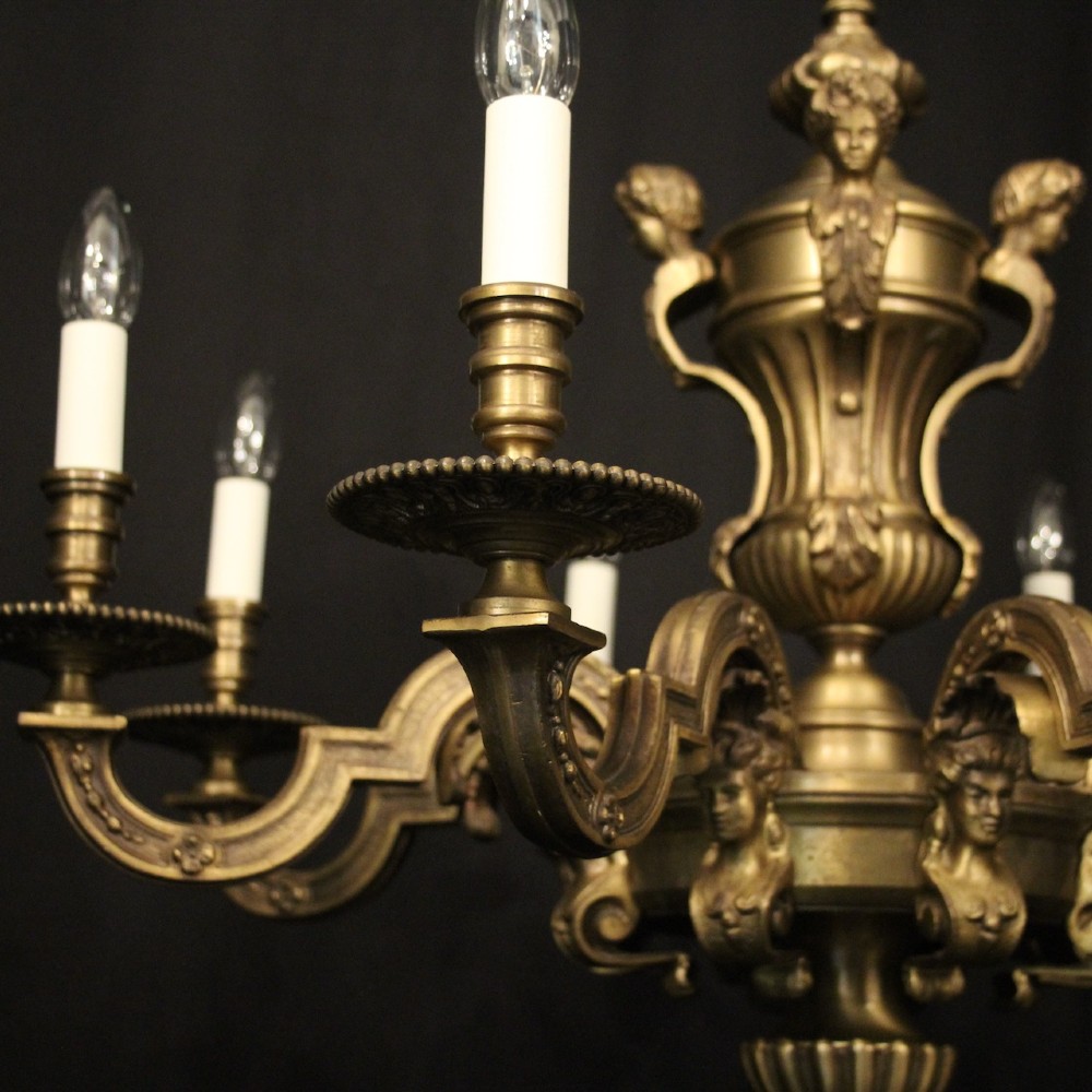 An eight-arm French gilt bronze chandelier featuring an urn-shaped central stem, cast classical busts, and candle-style bulb holders. View IV