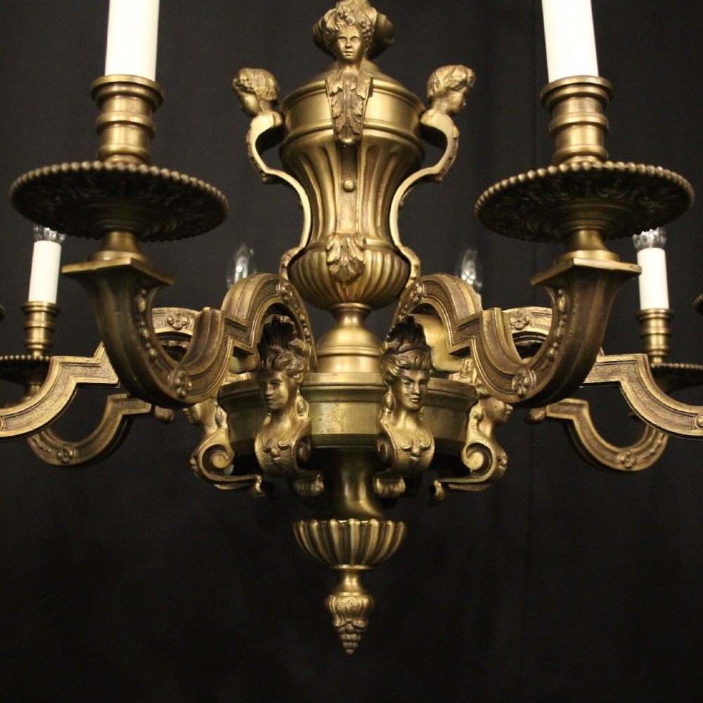 An eight-arm French gilt bronze chandelier featuring an urn-shaped central stem, cast classical busts, and candle-style bulb holders. View V