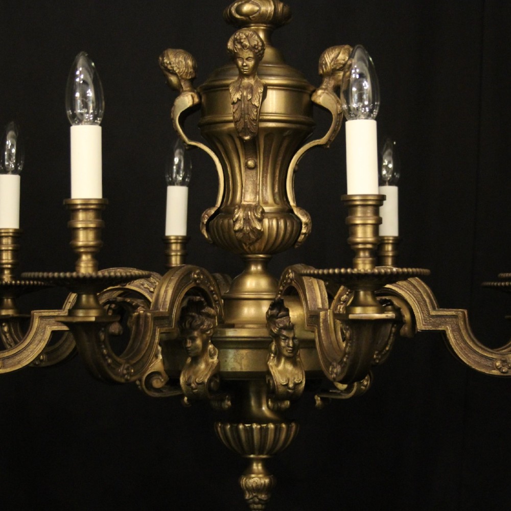 An eight-arm French gilt bronze chandelier featuring an urn-shaped central stem, cast classical busts, and candle-style bulb holders. View VII