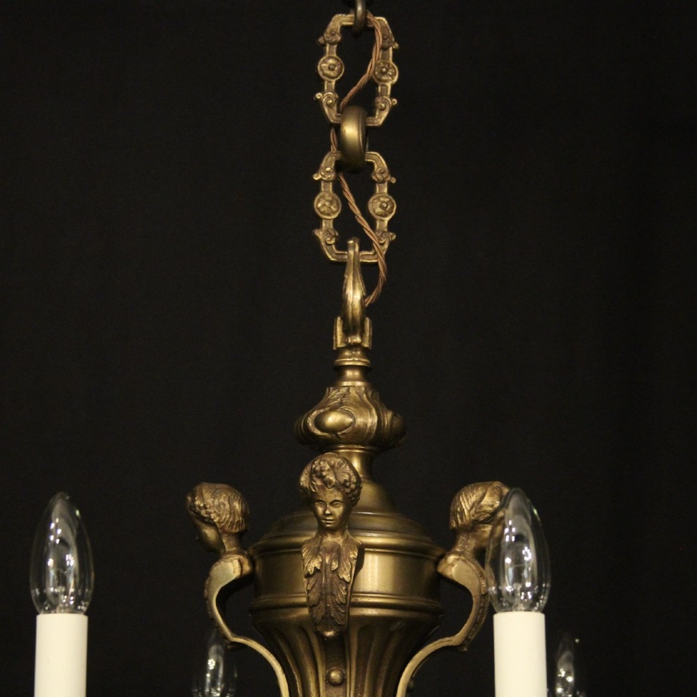 An eight-arm French gilt bronze chandelier featuring an urn-shaped central stem, cast classical busts, and candle-style bulb holders. View IX