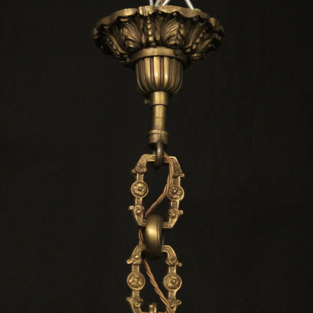 An eight-arm French gilt bronze chandelier featuring an urn-shaped central stem, cast classical busts, and candle-style bulb holders. View X