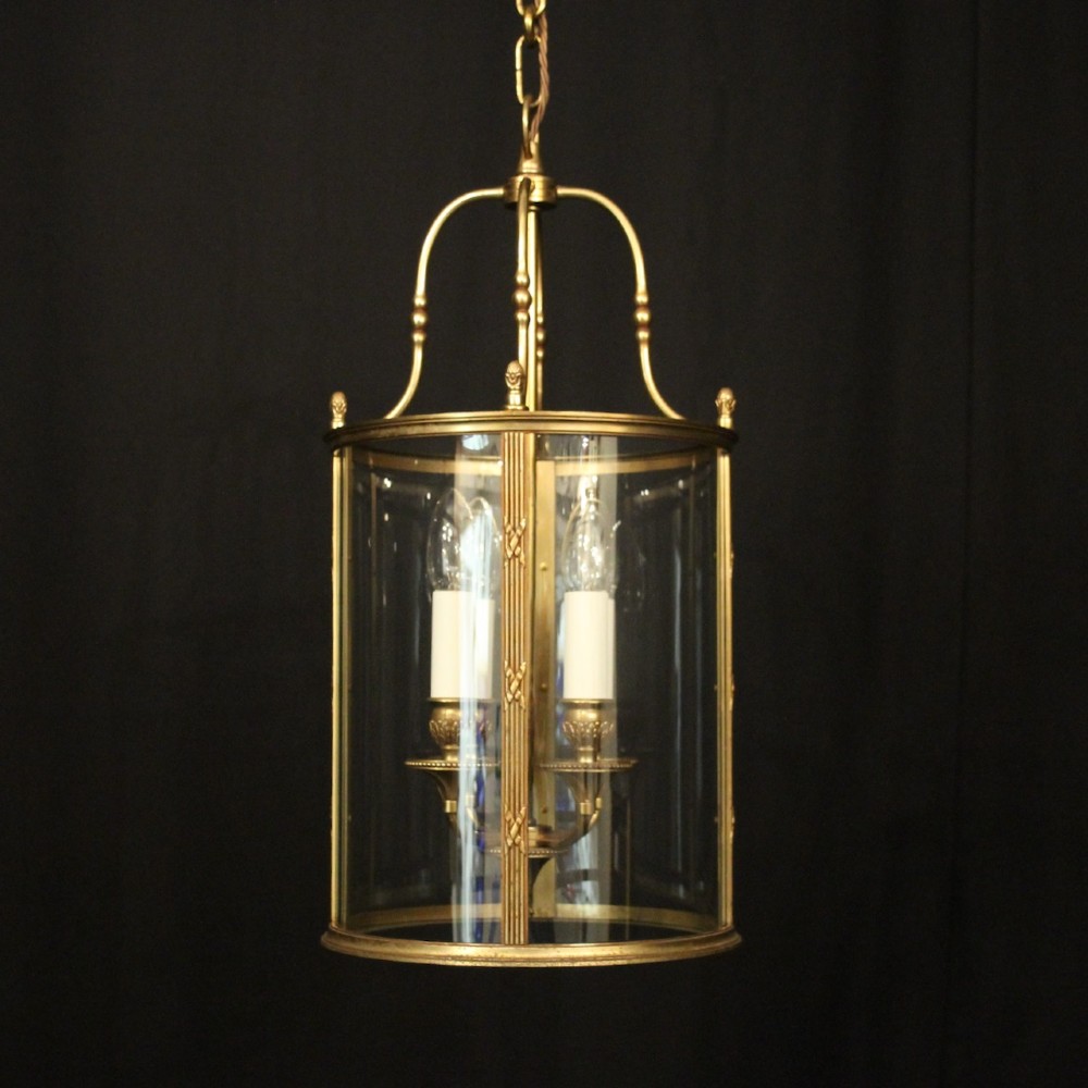 A cylindrical French gilded bronze hall lantern featuring curved glass panels and four internal candle-style light fittings.