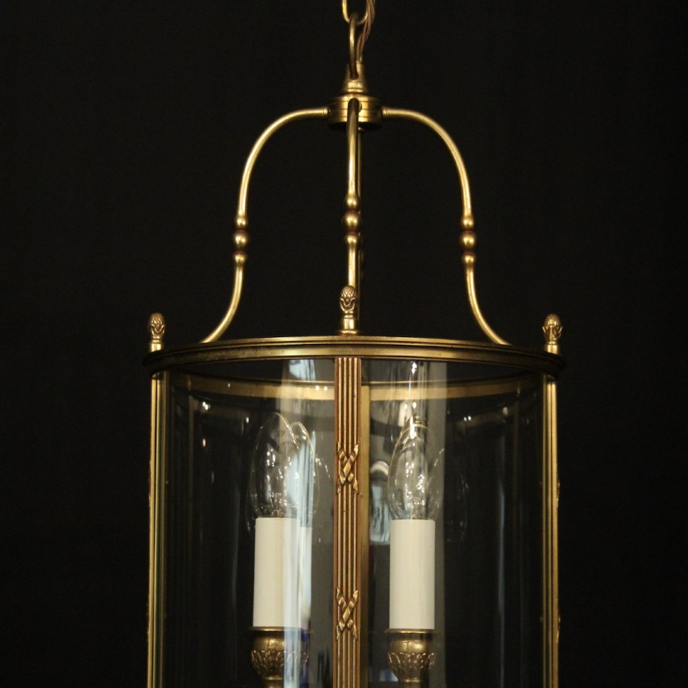 A cylindrical French gilded bronze hall lantern featuring curved glass panels and four internal candle-style light fittings. View II