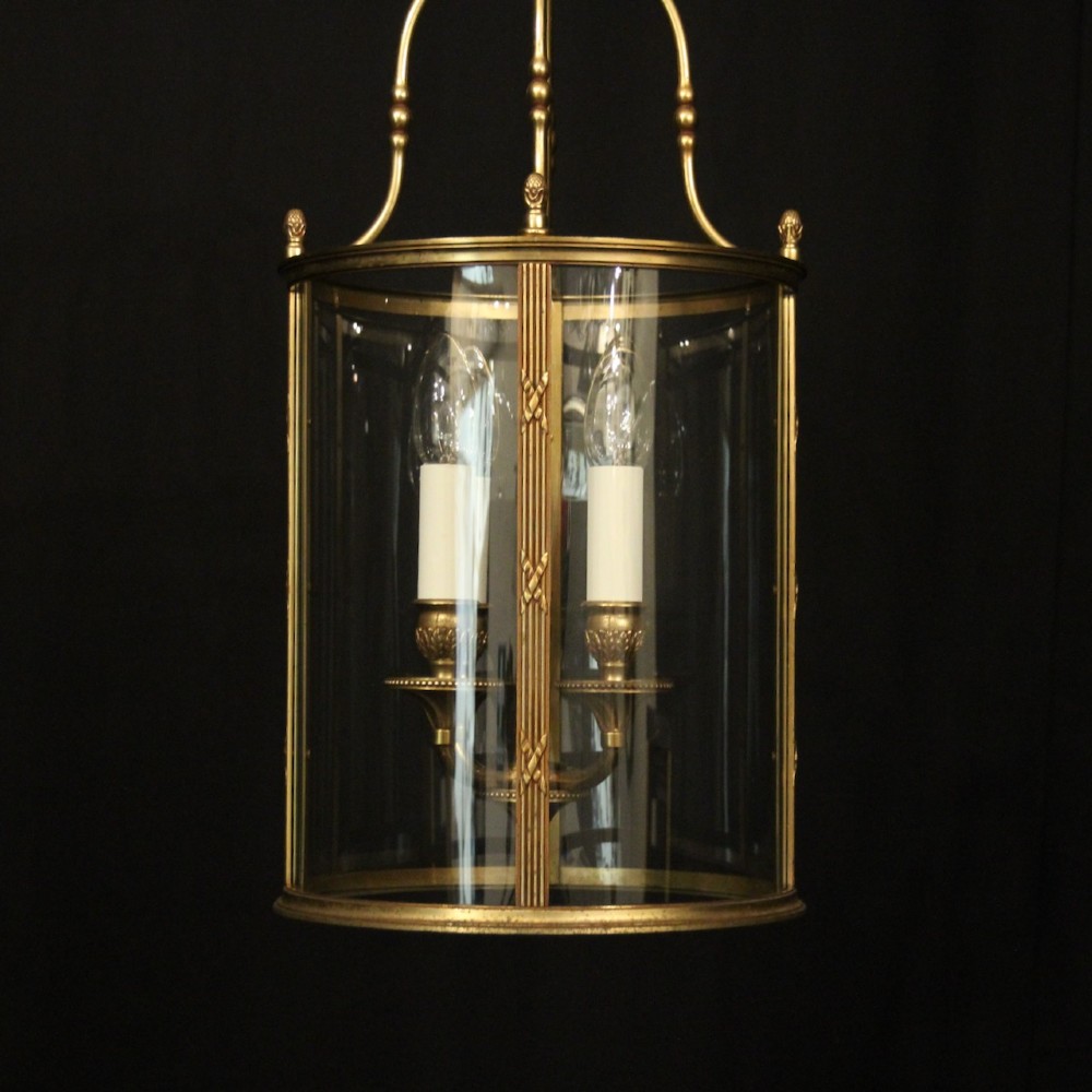 A cylindrical French gilded bronze hall lantern featuring curved glass panels and four internal candle-style light fittings. View III