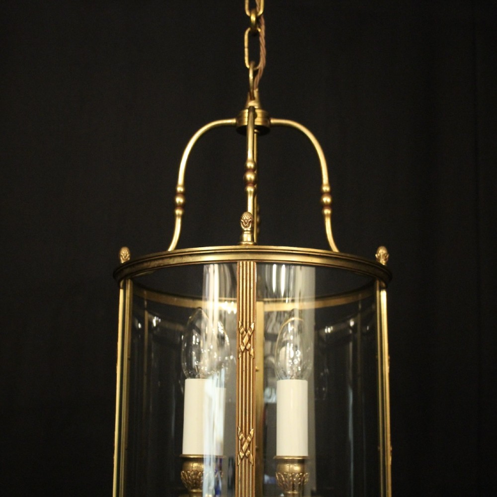 A cylindrical French gilded bronze hall lantern featuring curved glass panels and four internal candle-style light fittings. View V