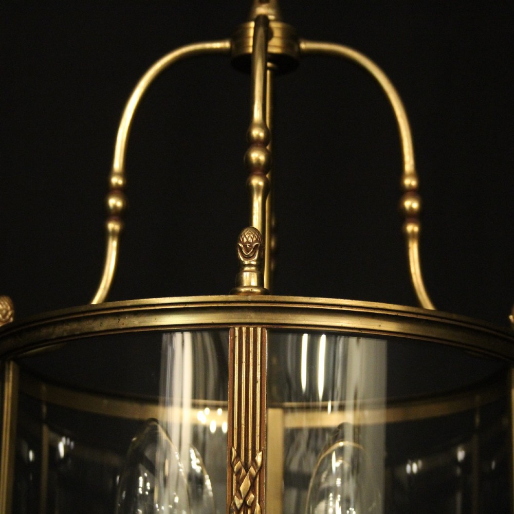 A cylindrical French gilded bronze hall lantern featuring curved glass panels and four internal candle-style light fittings. View VI