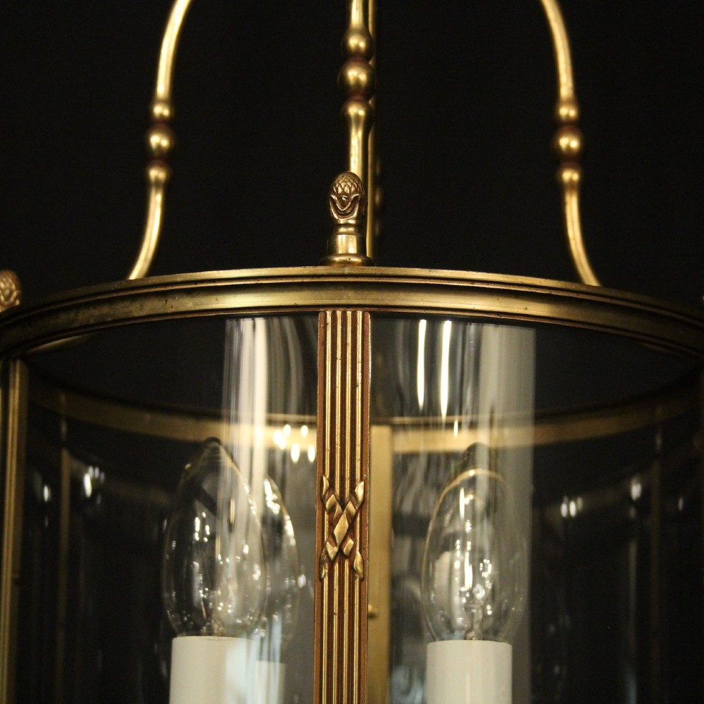 A cylindrical French gilded bronze hall lantern featuring curved glass panels and four internal candle-style light fittings. View VII