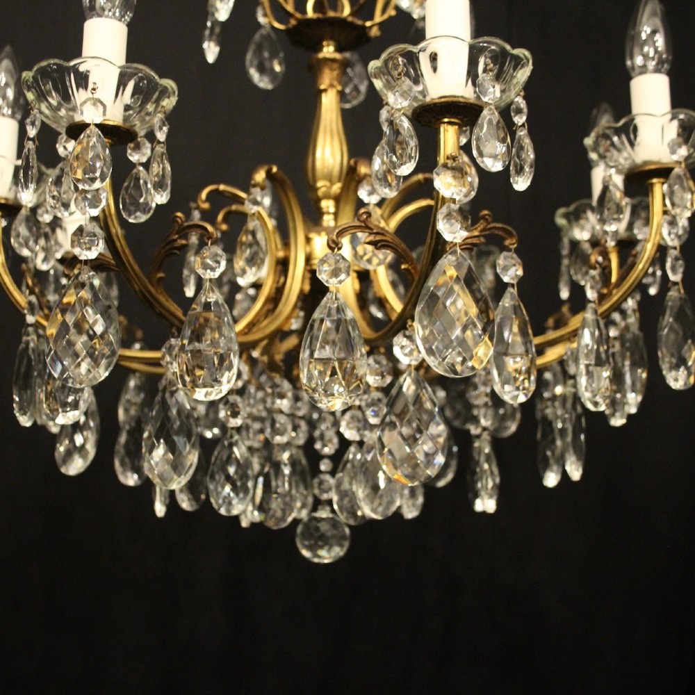 An eight-light French gilded brass chandelier featuring decorative scroll arms and hanging faceted crystal drops. View IV