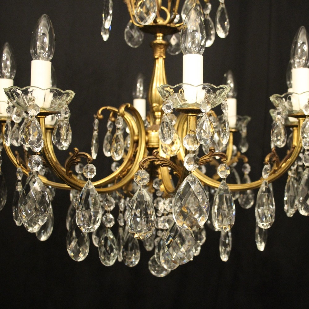 An eight-light French gilded brass chandelier featuring decorative scroll arms and hanging faceted crystal drops. View V