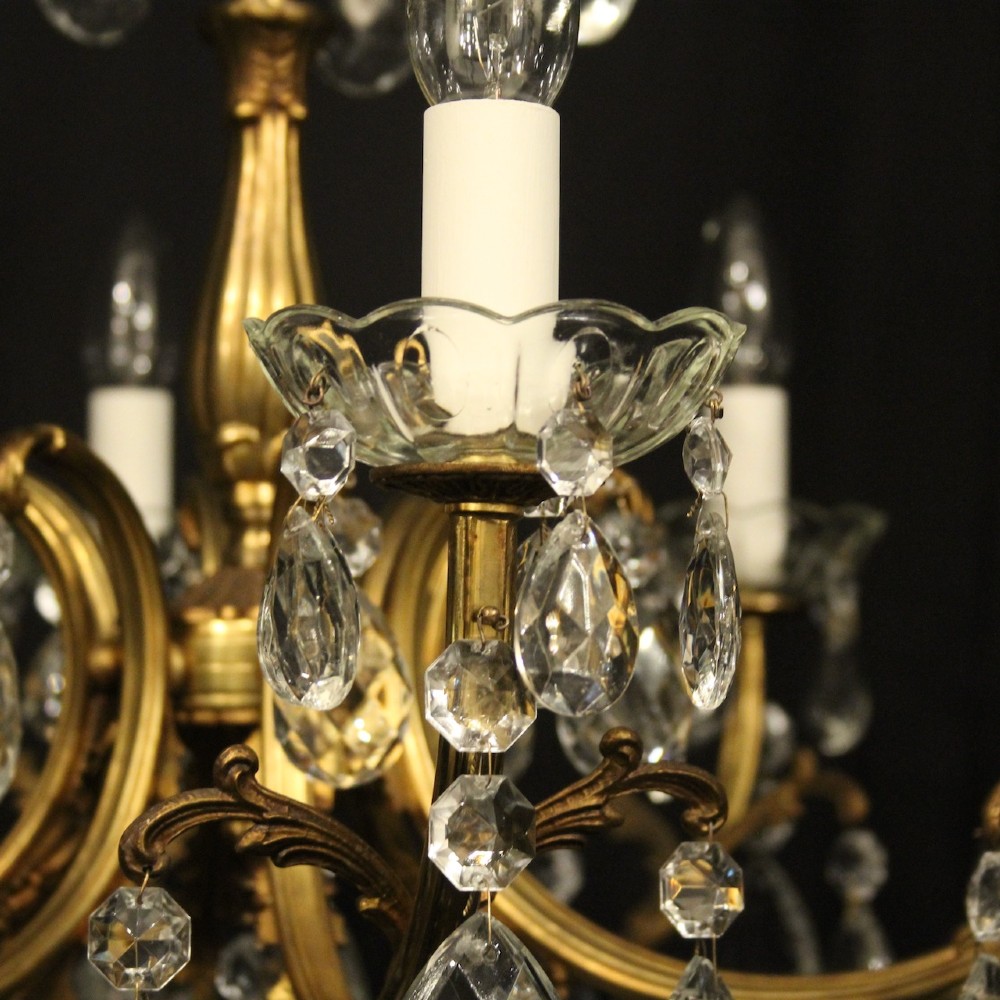 An eight-light French gilded brass chandelier featuring decorative scroll arms and hanging faceted crystal drops. View VII