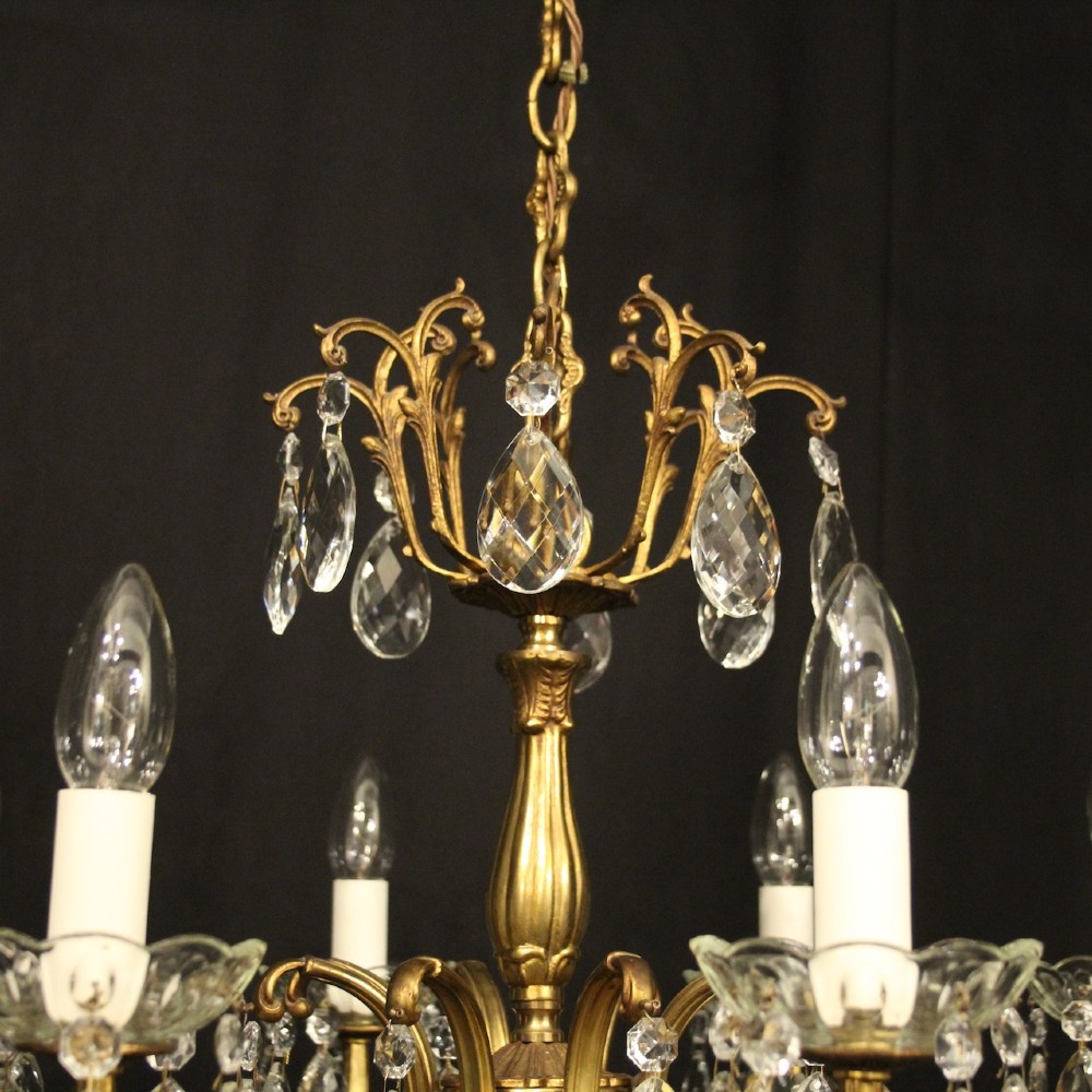 An eight-light French gilded brass chandelier featuring decorative scroll arms and hanging faceted crystal drops. View IX