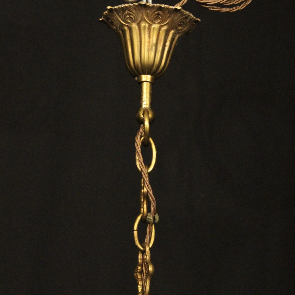 An eight-light French gilded brass chandelier featuring decorative scroll arms and hanging faceted crystal drops. View X