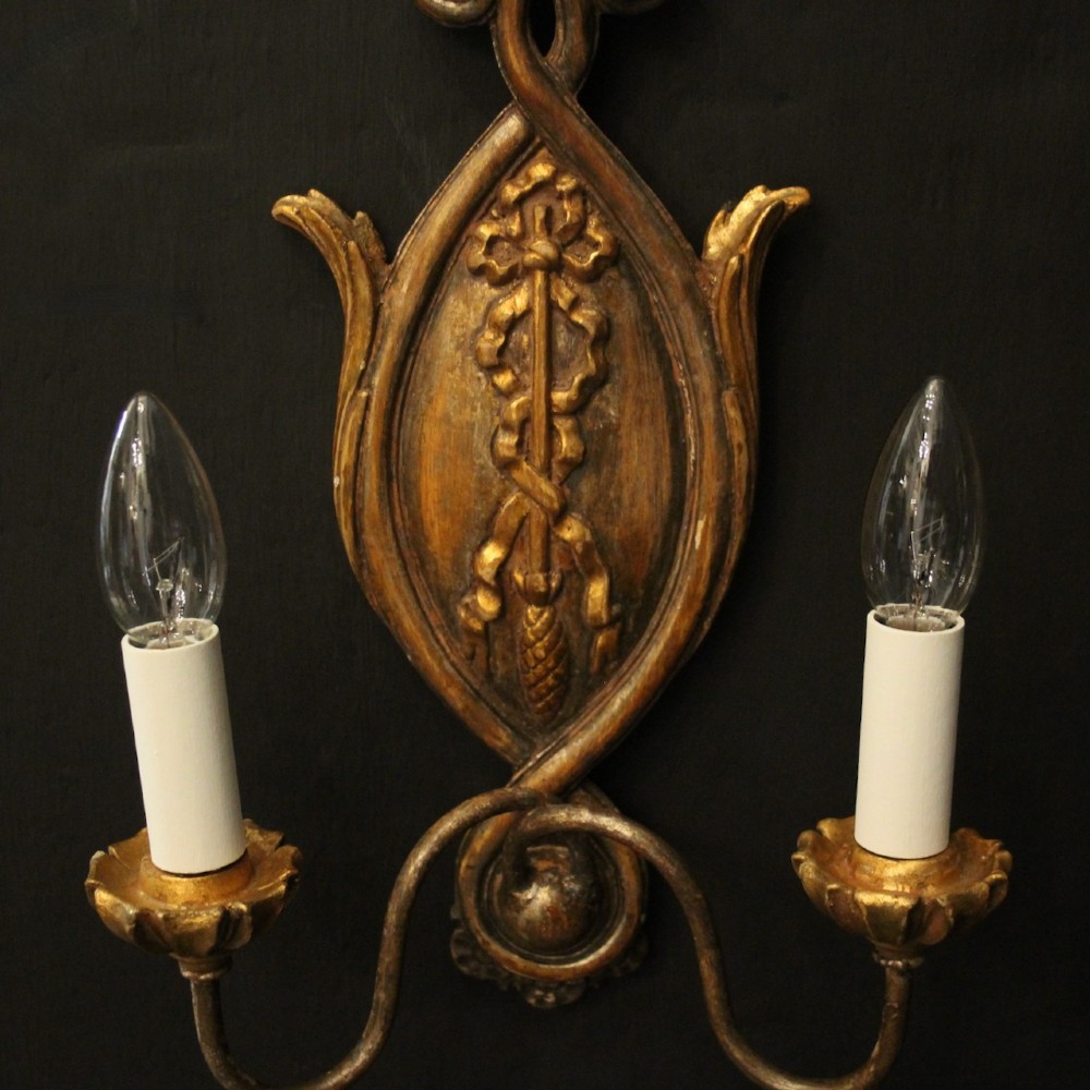 A pair of Florentine carved giltwood twin arm wall lights featuring ribbon and scroll motifs with white candle sleeves. View III