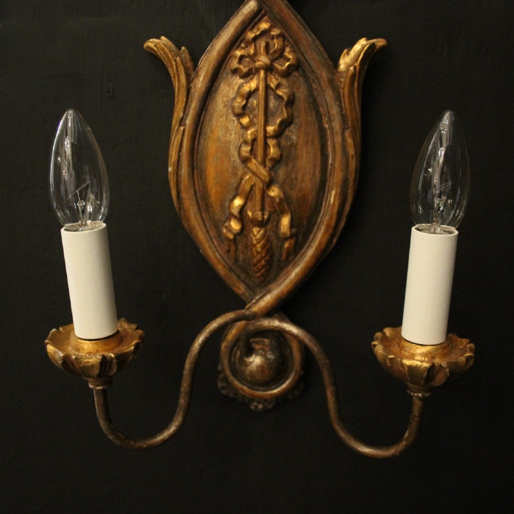 A pair of Florentine carved giltwood twin arm wall lights featuring ribbon and scroll motifs with white candle sleeves. View VI