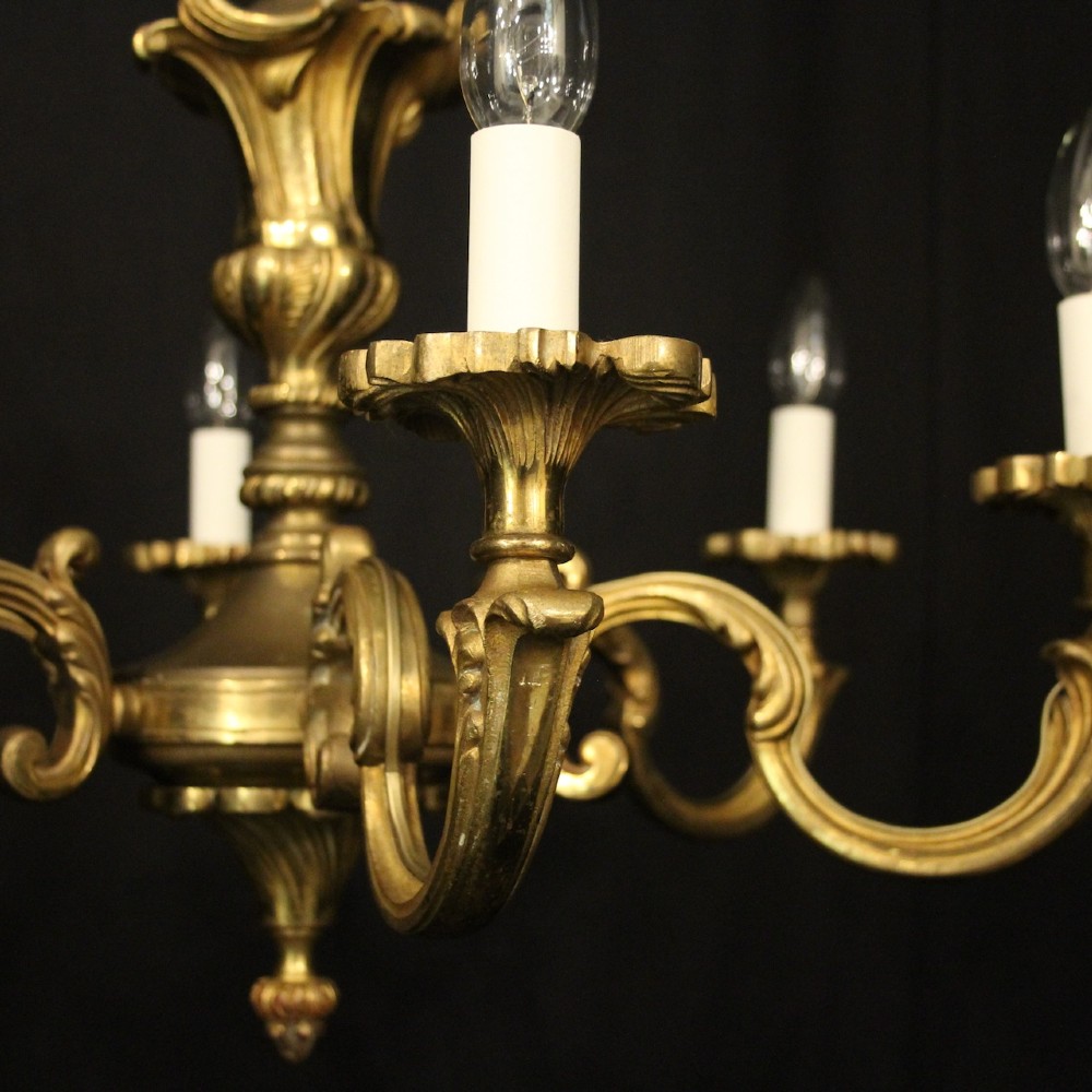 A six-arm French gilt bronze chandelier featuring scrolled arms, leaf motifs, and faux candle bulb holders hanging from a central column. View II