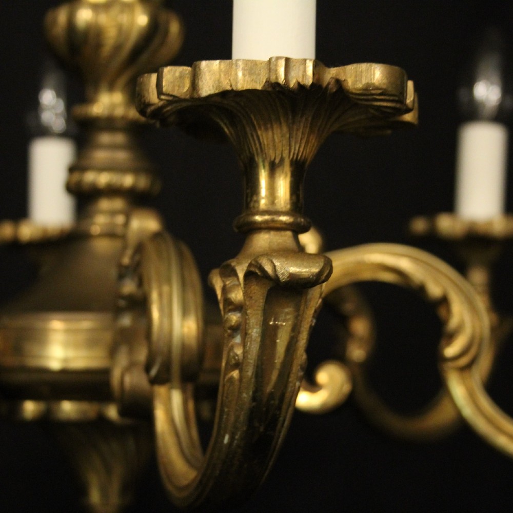 A six-arm French gilt bronze chandelier featuring scrolled arms, leaf motifs, and faux candle bulb holders hanging from a central column. View III