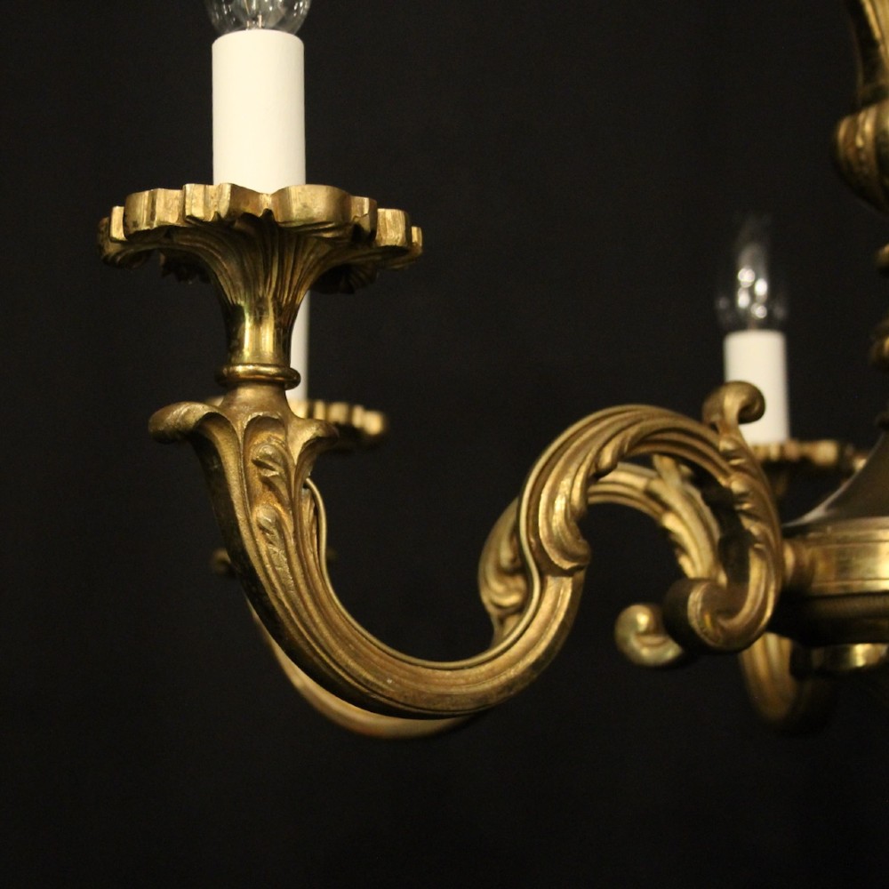 A six-arm French gilt bronze chandelier featuring scrolled arms, leaf motifs, and faux candle bulb holders hanging from a central column. View IV