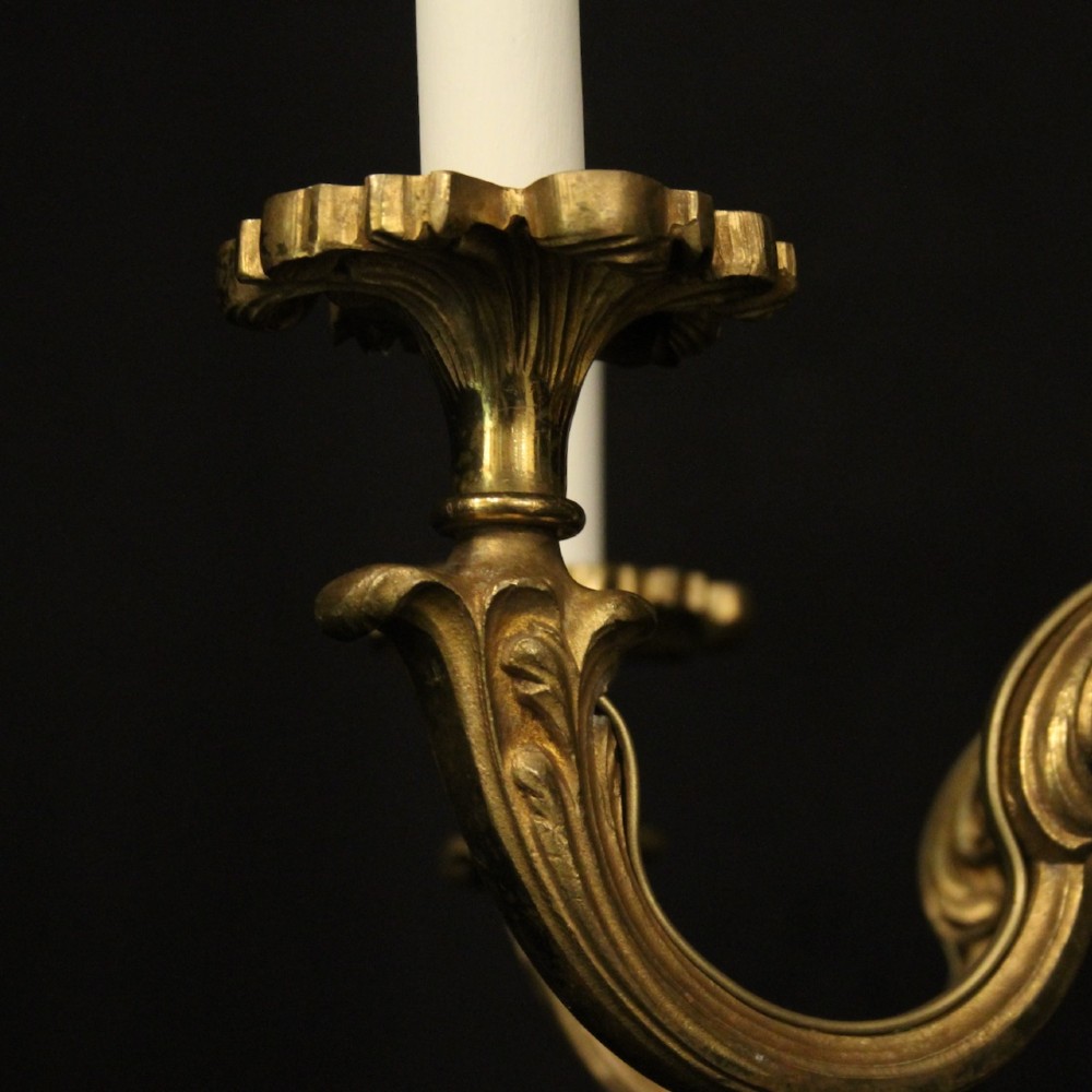 A six-arm French gilt bronze chandelier featuring scrolled arms, leaf motifs, and faux candle bulb holders hanging from a central column. View V