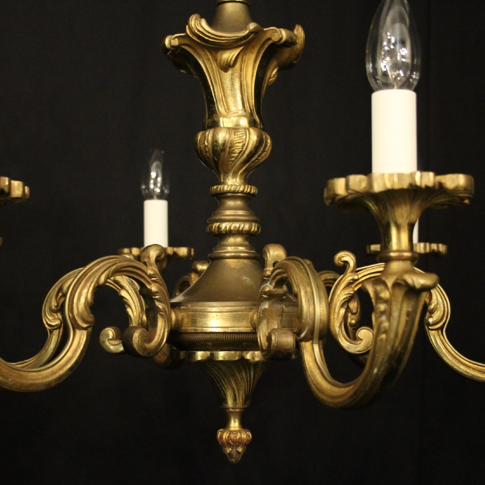 A six-arm French gilt bronze chandelier featuring scrolled arms, leaf motifs, and faux candle bulb holders hanging from a central column. View VI