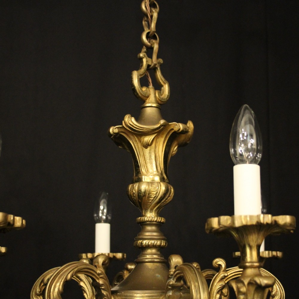 A six-arm French gilt bronze chandelier featuring scrolled arms, leaf motifs, and faux candle bulb holders hanging from a central column. View VIII