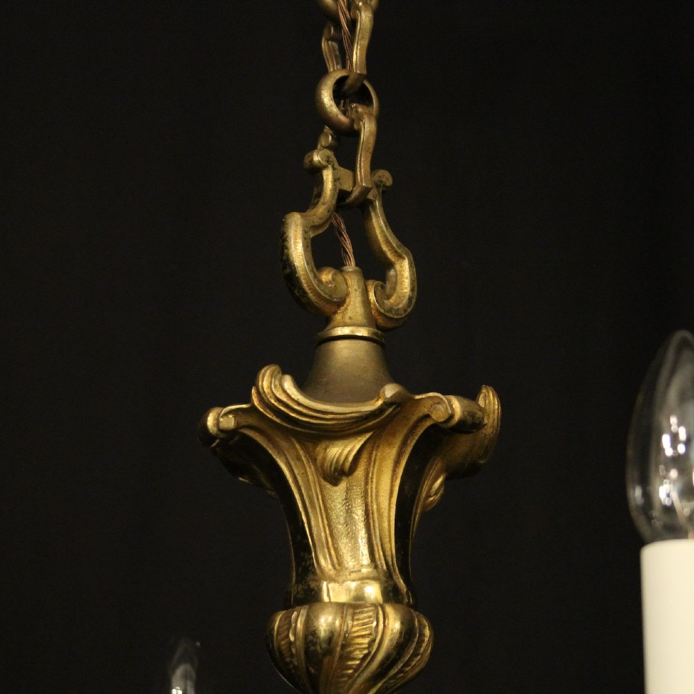 A six-arm French gilt bronze chandelier featuring scrolled arms, leaf motifs, and faux candle bulb holders hanging from a central column. View IX
