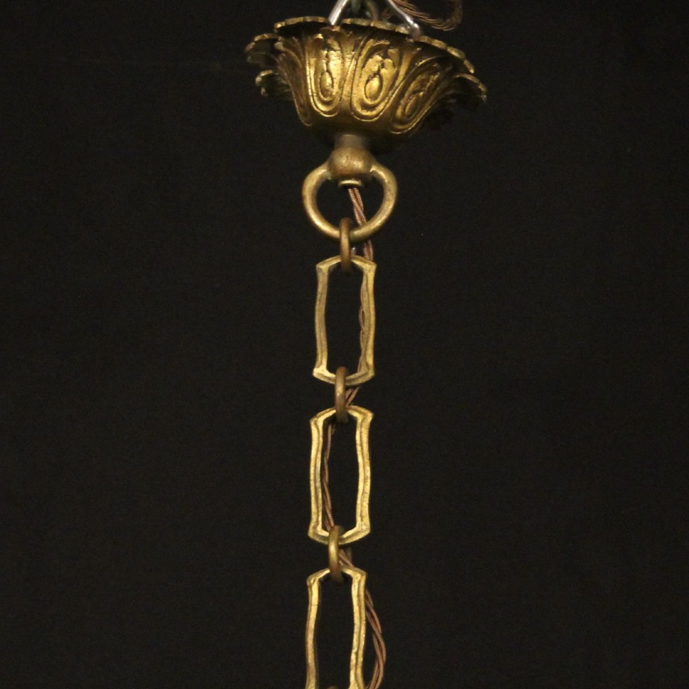 A French gilded bronze twelve-light chandelier featuring curved scrolling arms, cream candle-style light holders, and cascading faceted crystal drops. View X
